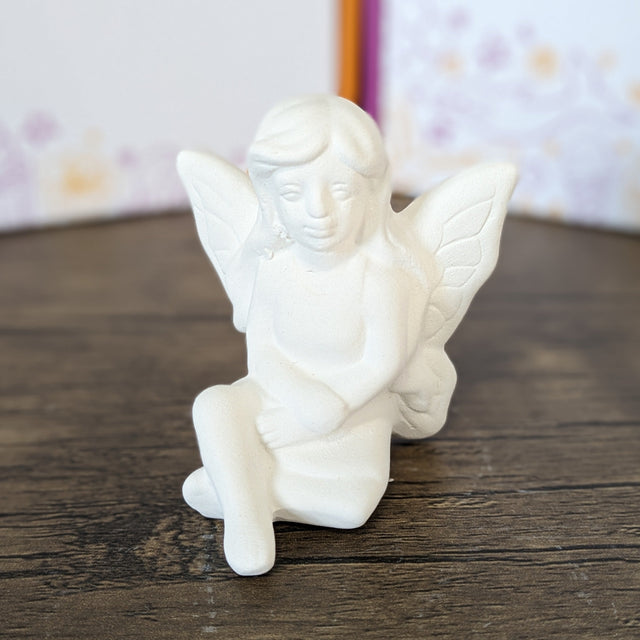 Unpainted pottery bisque seated small fairy, front view