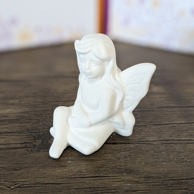 Unpainted pottery bisque seated small fairy, 3/4 view